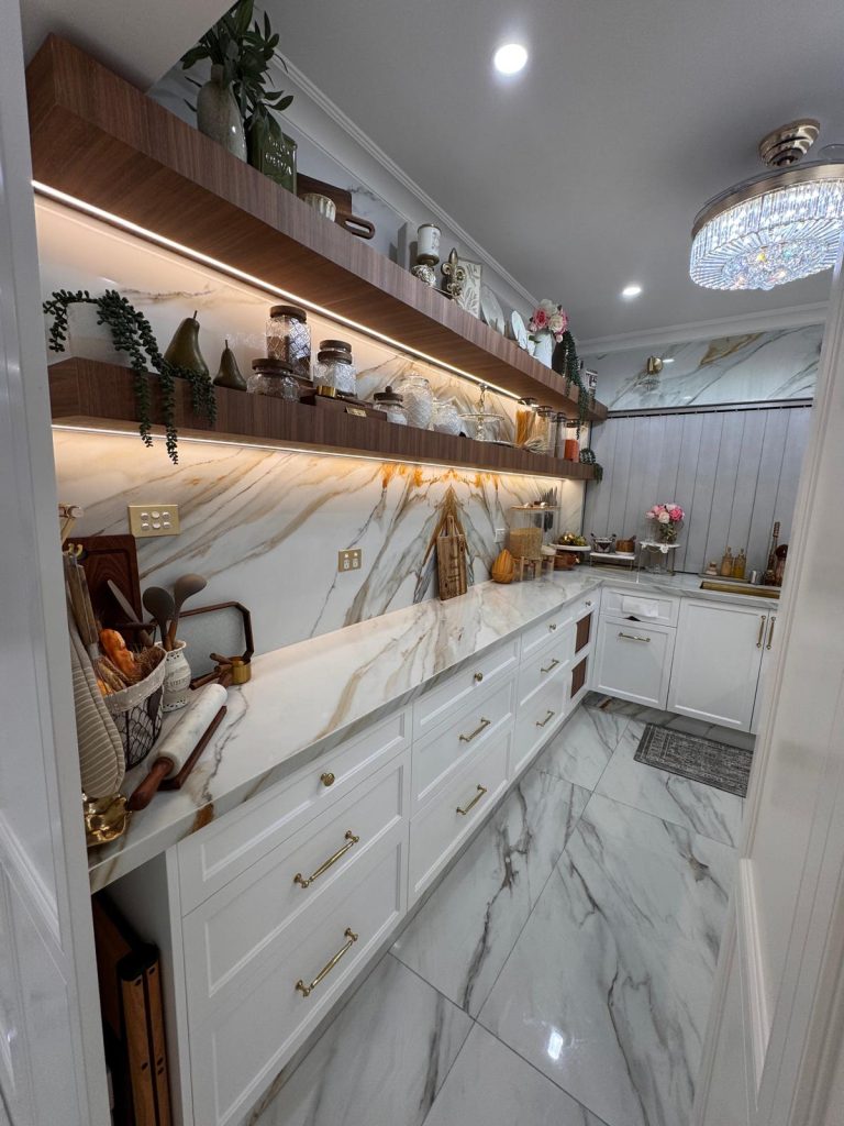 Butler's pantry with lit timber floating shelves, white shaker cabinets and marble-look benchtops.