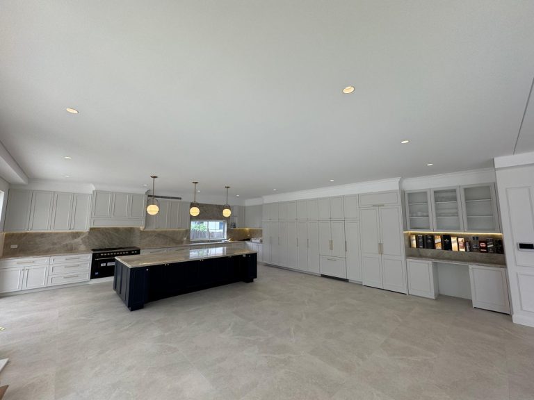 Large open-plan kitchen with a navy island, white shaker cabinetry and a full-height pantry wall.